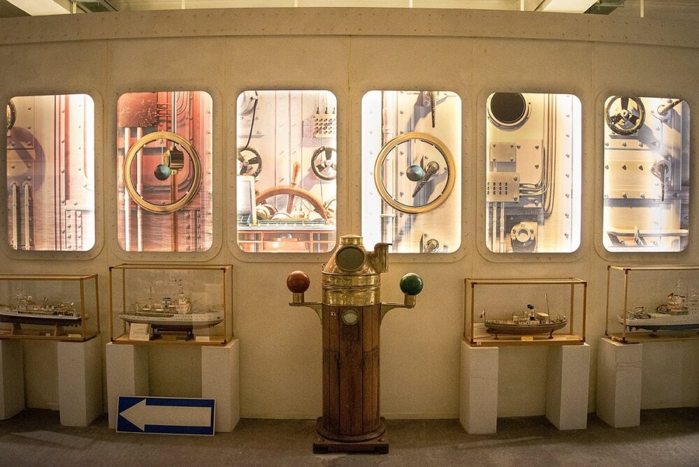 sala del museo navale di imperia con vari oggetti dedicati all'esperienza della navigazione e dei modellini di navi all'interno di teche di vetro