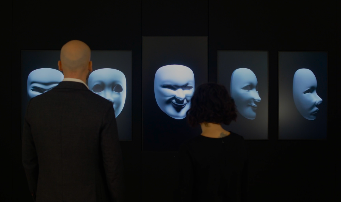 uomo di spalle che osserva la proiezione immersiva di alcune maschere, realizzata da ETT per la Casa Museo Luigi Pirandello