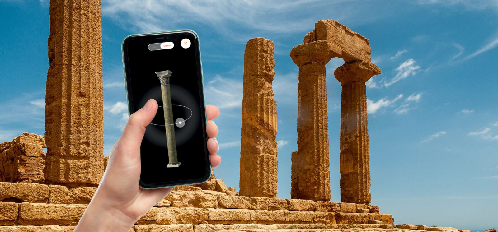 mano con cellulare iphone che utilizza l'applicazione augustus, realizzata da ett, sullo sfondo rovine greche di un tempio