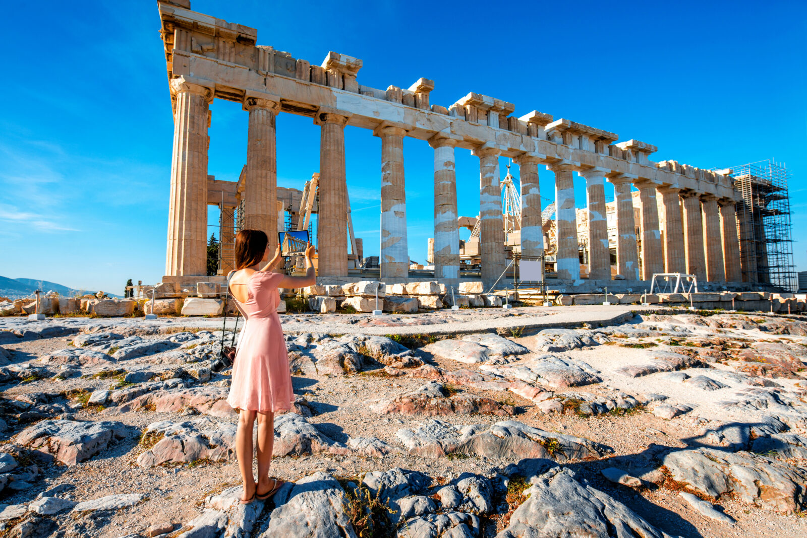 Giovane donna turista che fotografa con un tablet un tempio greco nell'acropoli