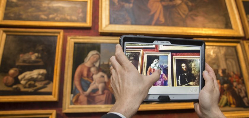 mani di un uomo che fotografa con un tablet i quadri di dipinti sulla parete presso la Gallerie dell'accademia, di cui ett ha riprogettato l'esperienza di visita in collaborazione con samsung