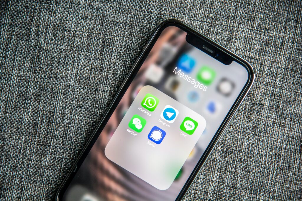 foto di un iphone sbloccato sulla schermata principale con alcune applicazioni di una cartella specifica messages: whatsapp, telegram, line, wechat, signal