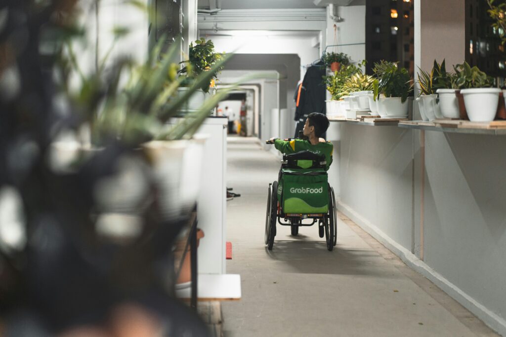 bambino su sedia a rotelle che percorre un corridoio pieno di vasi con piantine