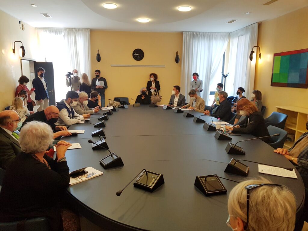 Immagine della conferenza stampa 100 Luzzati con tavola ovale e partecipanti seduti