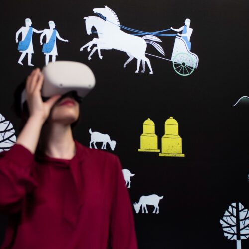 Ragazza a mezzo busto con visore presso MIA Avella, Museo Immersivo e Archeologico di Avella situato presso il Palazzo Baronale, il cui percorso immersivo è realizzato da ett, su sfondo nero con logo mia avella e immagini stilizzate che rievocano il museo