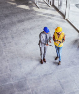 Due uomini con caschetti colorati che devono affrontare un'operazione di manutenzione all'interno di un edificio