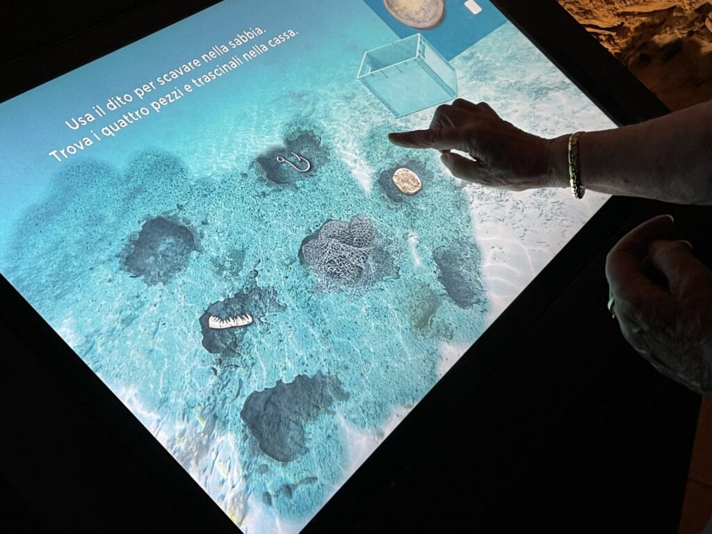 mano di donna che tocca schermo touch che fa vedere il fondale del mare in un gioco interattivo, presso Santa Margherita Ligure, parte dell'allestimento multimediale di ETT