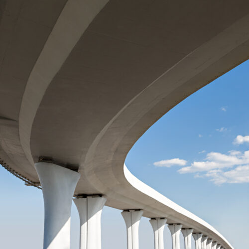 sezione di ponte vista dal passo, con piloni nella parte inferiore e cielo azziuro con alcune nuvole sulla destra nello sfondo