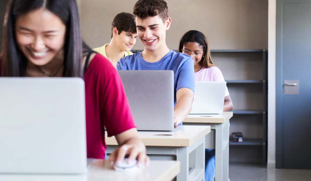 Ragazzi in aula che usano il pc sorridendo