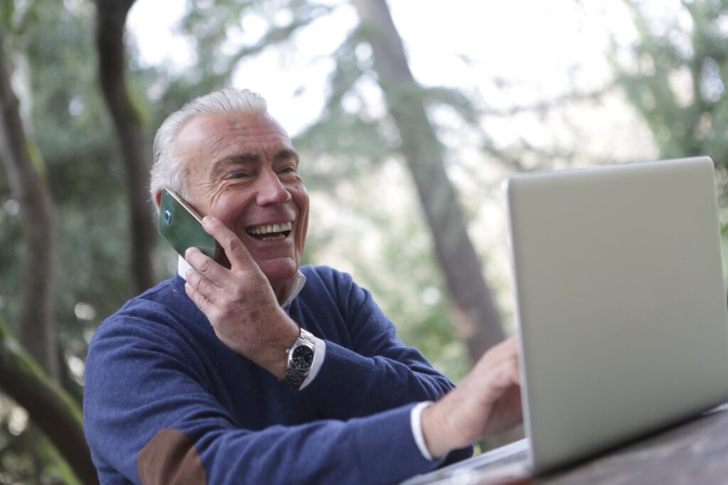 uomo che parla al telefono e consulta il pc