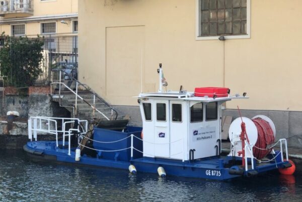 piccolo peschereccio blu e bianco attraccato ad un porticciolo vicino ad un edificio