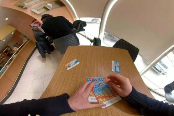 foto distorta di mani mentre giocano con un gratta e vinci in un tavolino al bar, sulla sinistra il bancone