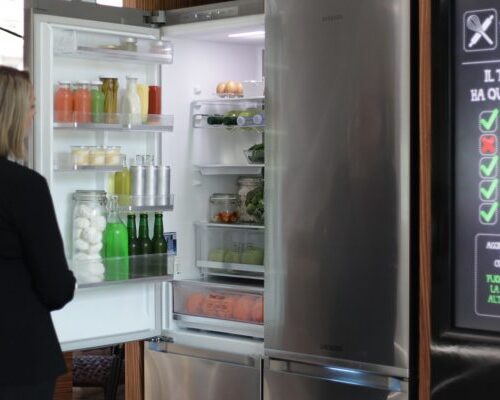 installazione Samsung SmartHome a milano, dettaglio sulla funzionalità del frigo, una ragazza che apre e guarda dentro al frigorifero smart, i visitatori possono testare l’efficienza di una gestione “smart” della casa