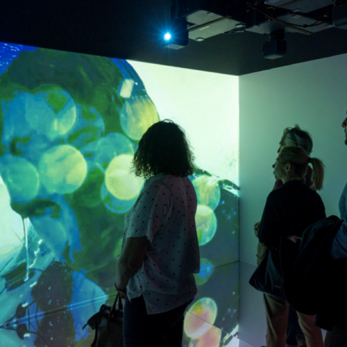 foto di alcune persone mentre guardano la proiezione delle aree iconiche della città e della liguria all'interno della camera immersiva realizzata da ETT per il genoa pavillon dell'ocean race