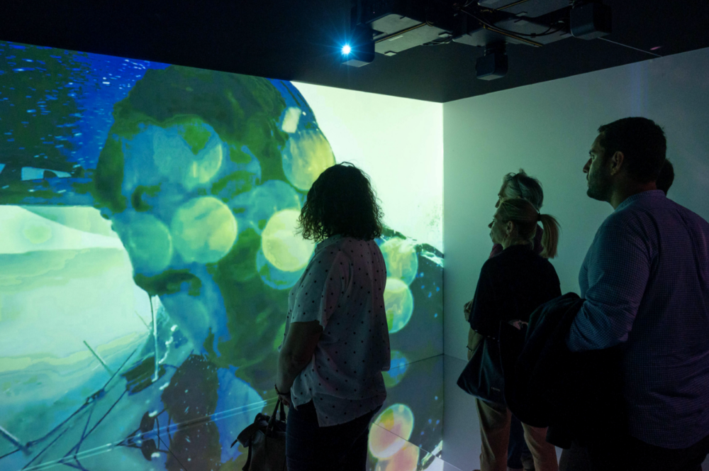 foto di alcune persone mentre guardano la proiezione delle aree iconiche della città e della liguria all'interno della camera immersiva realizzata da ETT per il genoa pavillon dell'ocean race