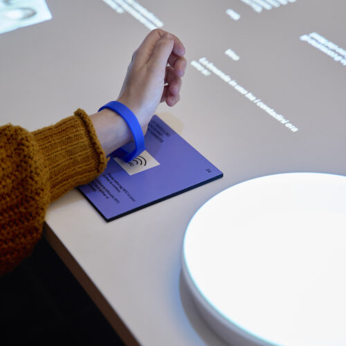 braccialetto con sensore al polso di una donna che aziona degli elementi interattivi all'interno del museo dell'emigrazione italiana (MEI)