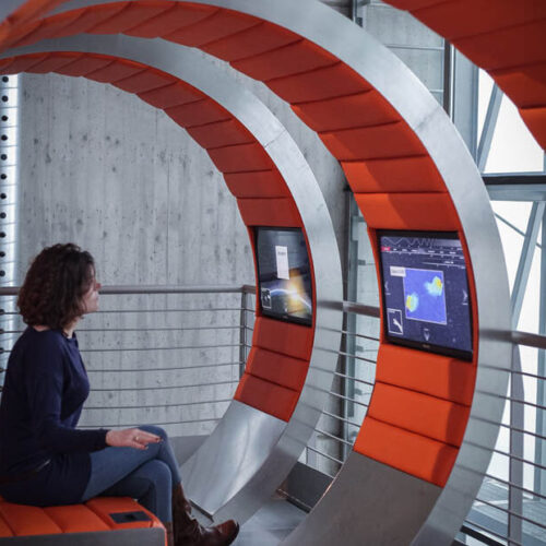 donna seduta davanti exhibit multimediale che le permette di partire per un viaggio immersivo e multisensoriale alla scoperta del cosmo, nel percorso rinnovato da ett del planetario di torino