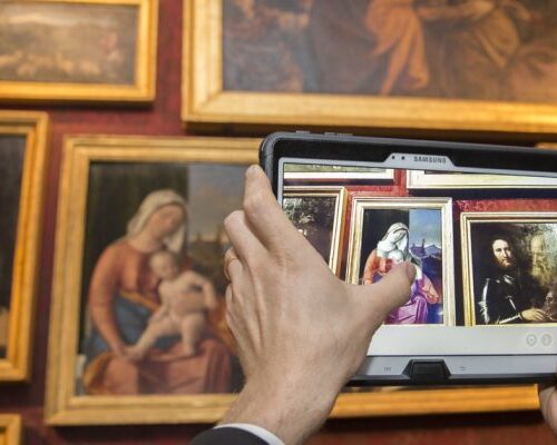 mani di un uomo che fotografa con un tablet i quadri di dipinti sulla parete presso la Gallerie dell'accademia, di cui ett ha riprogettato l'esperienza di visita in collaborazione con samsung