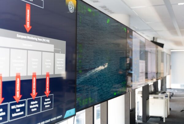 foto di diversi schermi uno di fianco all'altro all'interno di un ufficio appesi a una lunga parete, dove si vedono immagini nell'ambito di monitoraggio delle acque