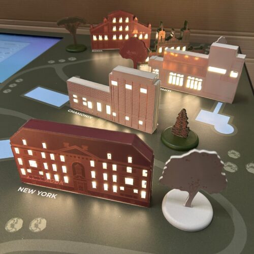 dettaglio delle 12 miniature 3d rappresentative dei diversi centri QC Terme disposte su un tavolo touch interattivo al centro del quale si trovano due monitor